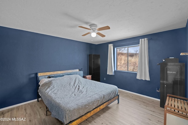 bedroom featuring ceiling fan, light hardwood / wood-style floors, and a textured ceiling