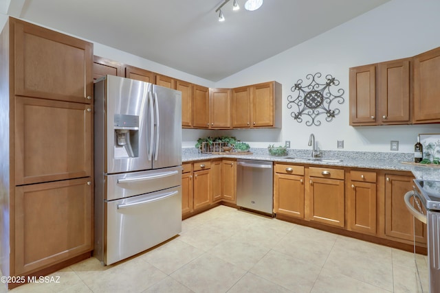 kitchen featuring sink, light stone counters, vaulted ceiling, light tile patterned flooring, and appliances with stainless steel finishes