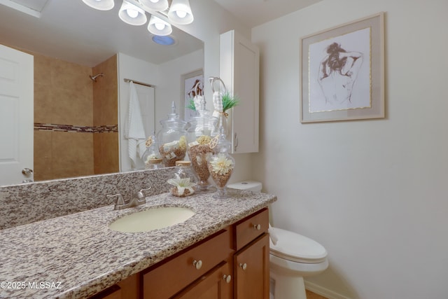 bathroom with vanity, toilet, and a tile shower