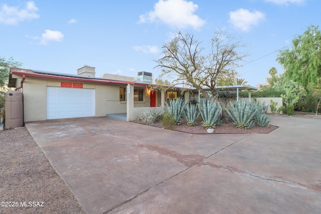 ranch-style home with solar panels, cooling unit, and a garage