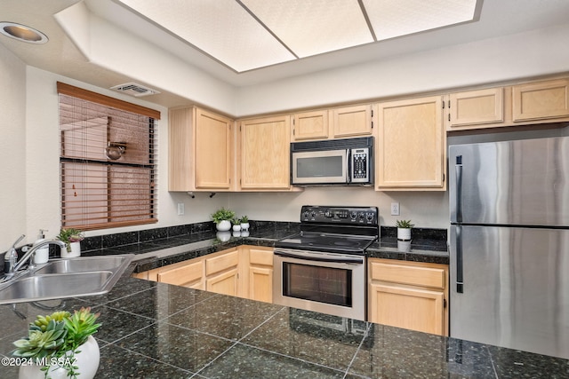 kitchen with light brown cabinets, range with electric cooktop, stainless steel refrigerator, and sink