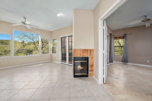 unfurnished living room featuring a tile fireplace, ceiling fan, and light tile patterned flooring