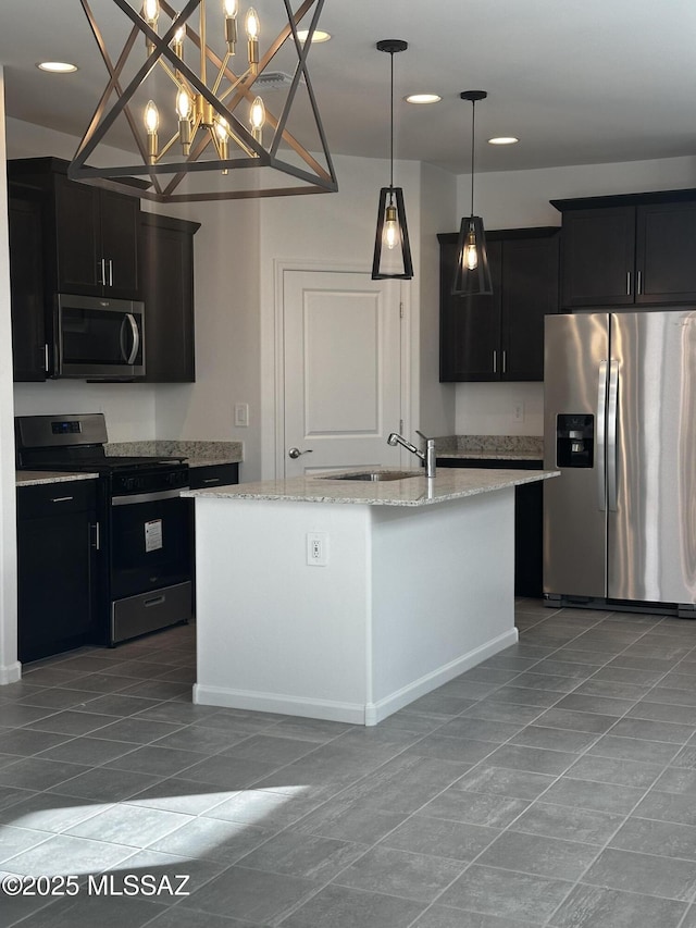 kitchen featuring sink, decorative light fixtures, appliances with stainless steel finishes, light stone countertops, and a kitchen island with sink