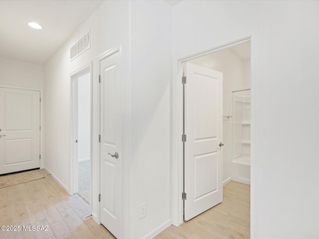 hallway with light wood-style floors, recessed lighting, visible vents, and baseboards