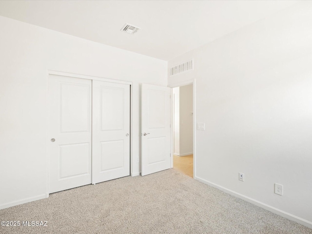 unfurnished bedroom with baseboards, a closet, visible vents, and light colored carpet