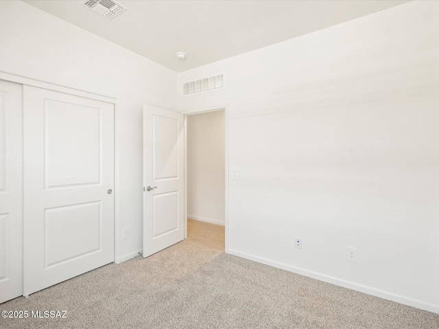 unfurnished bedroom with light colored carpet, a closet, visible vents, and baseboards