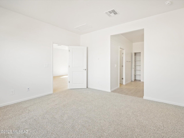 unfurnished room featuring baseboards, visible vents, and light colored carpet