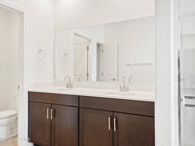 bathroom featuring toilet, double vanity, and a sink