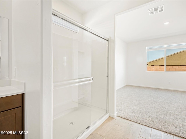 full bath with a stall shower, baseboards, visible vents, wood finished floors, and vanity