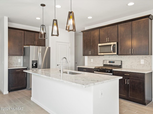 kitchen featuring an island with sink, dark brown cabinetry, stainless steel appliances, and a sink