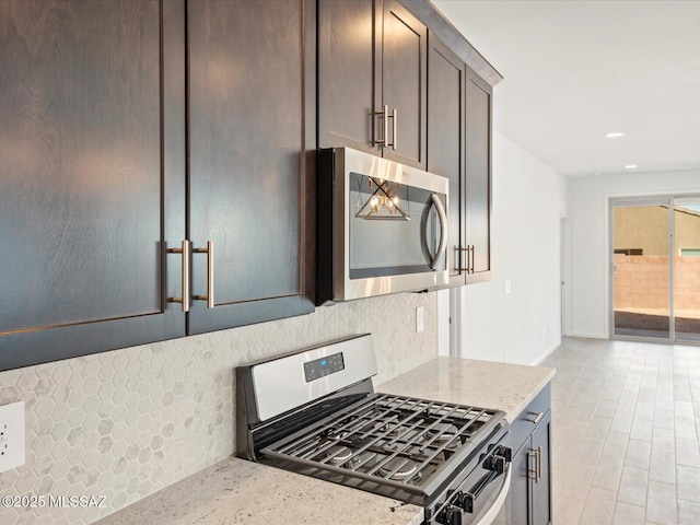 kitchen featuring light stone counters, dark brown cabinetry, recessed lighting, appliances with stainless steel finishes, and decorative backsplash