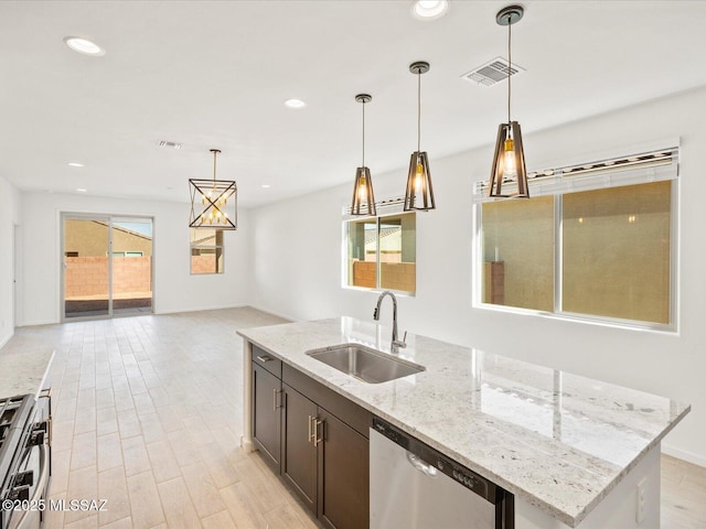 kitchen featuring a center island with sink, visible vents, appliances with stainless steel finishes, light stone counters, and a sink