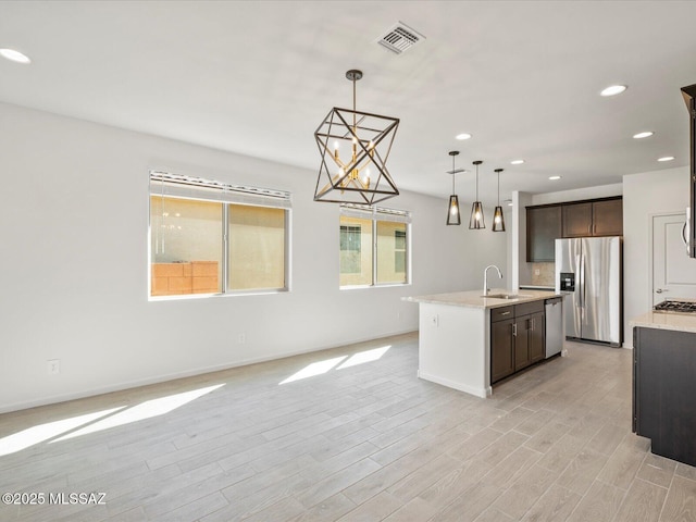 kitchen with open floor plan, hanging light fixtures, appliances with stainless steel finishes, and a sink