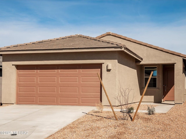 view of front of house featuring concrete driveway, a tile roof, an attached garage, and stucco siding