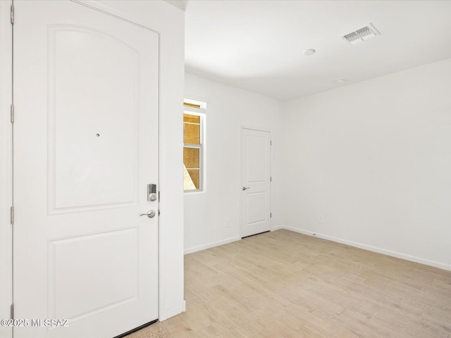 empty room featuring baseboards, visible vents, and light wood-style floors