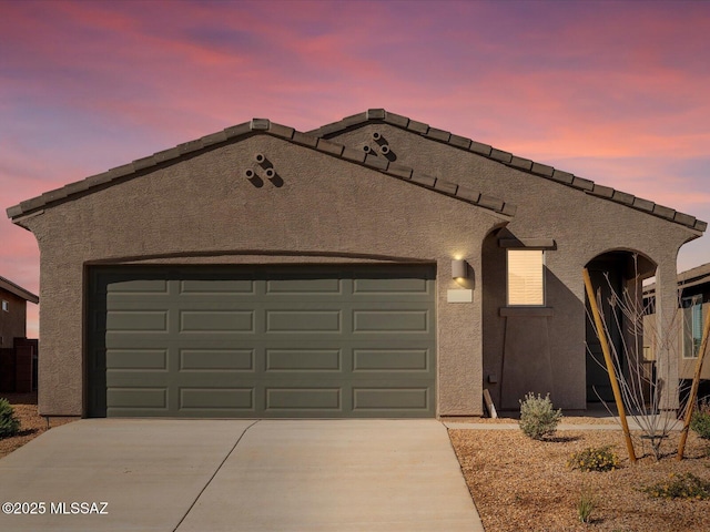 view of front of house featuring a garage, concrete driveway, and stucco siding