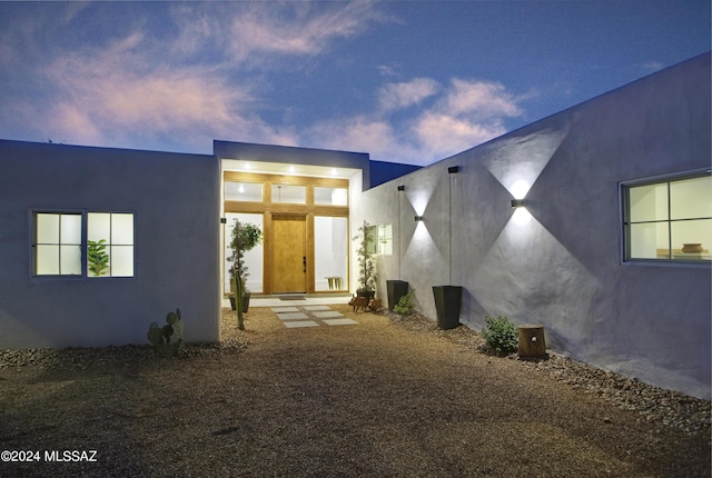 exterior entry at dusk featuring stucco siding