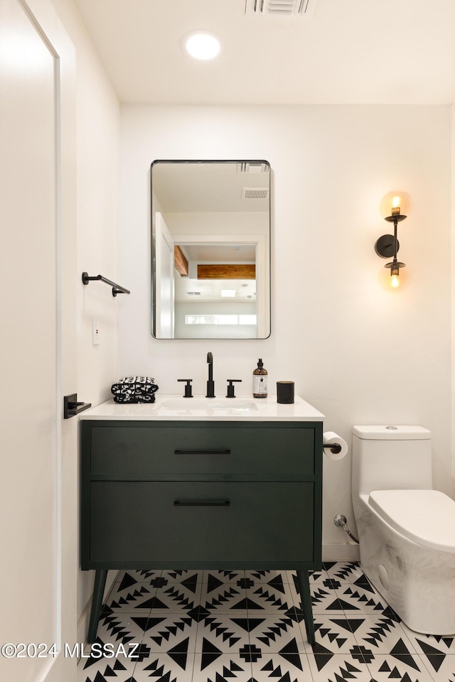 bathroom with toilet, vanity, and tile patterned floors