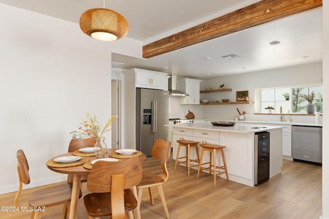 kitchen with beverage cooler, visible vents, wall chimney exhaust hood, stainless steel appliances, and light countertops