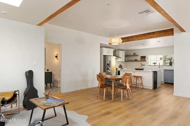 dining area with beamed ceiling and light hardwood / wood-style flooring