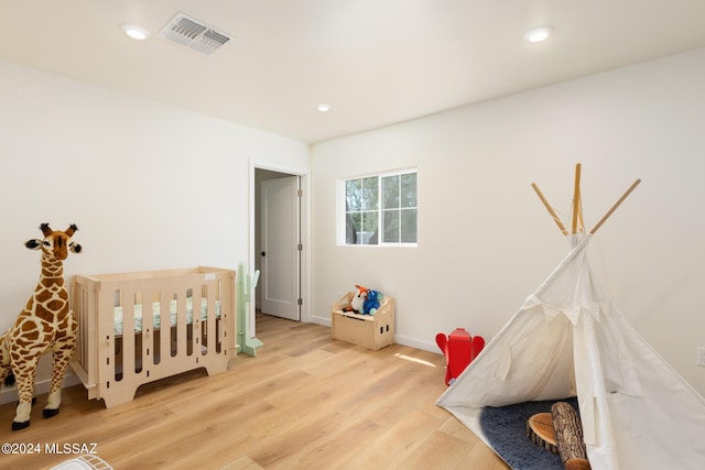 bedroom with baseboards, wood finished floors, visible vents, and recessed lighting