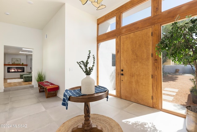 entryway with light tile patterned floors and a glass covered fireplace