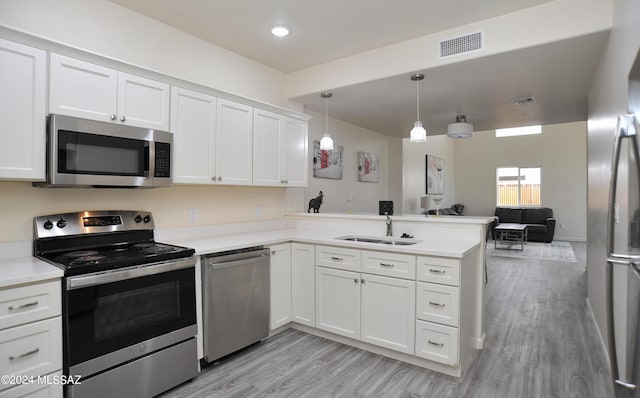 kitchen featuring kitchen peninsula, white cabinetry, decorative light fixtures, and appliances with stainless steel finishes