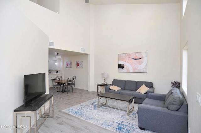 living room featuring light wood-type flooring and a high ceiling