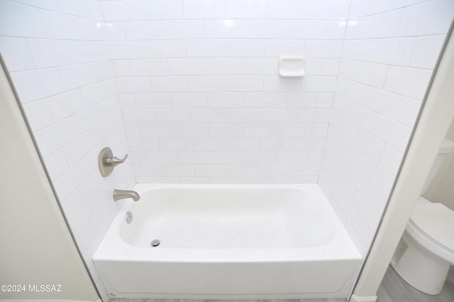 bathroom with toilet and tiled shower / bath