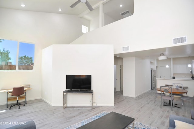 living room with light hardwood / wood-style floors, high vaulted ceiling, and ceiling fan