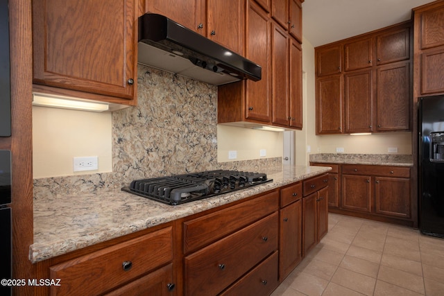 kitchen with black appliances, decorative backsplash, light tile patterned flooring, and light stone counters