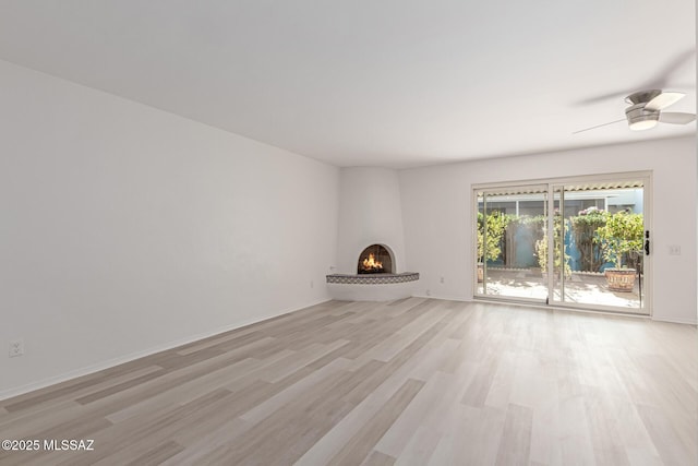 unfurnished living room with ceiling fan, light hardwood / wood-style floors, and a fireplace