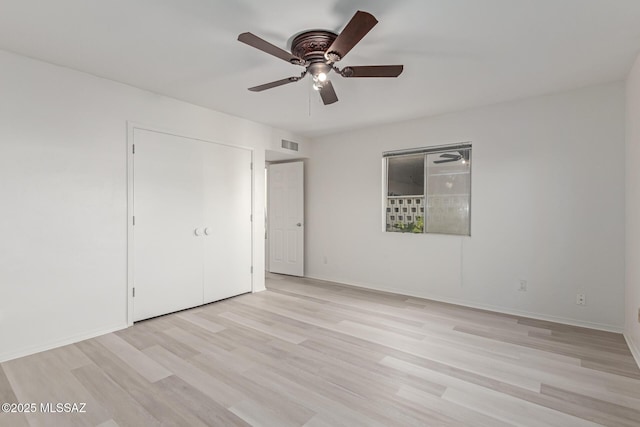 unfurnished bedroom featuring ceiling fan, a closet, and light wood-type flooring