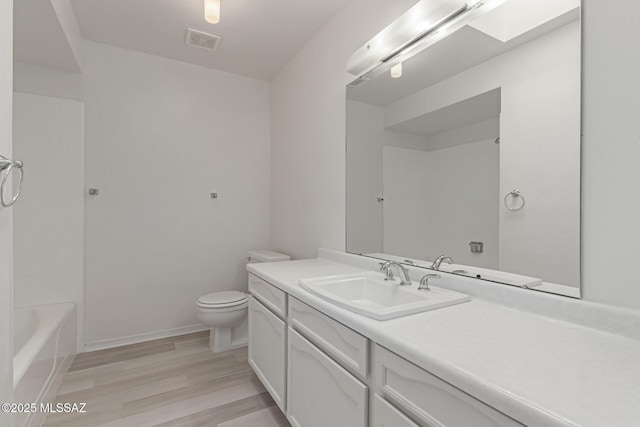 full bathroom featuring a skylight, wood-type flooring,  shower combination, toilet, and vanity