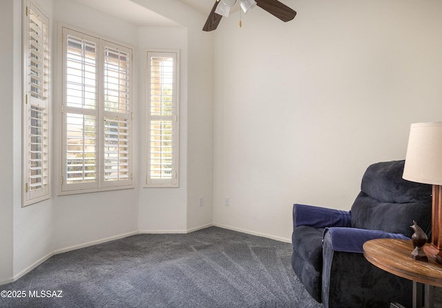 sitting room with ceiling fan and dark colored carpet