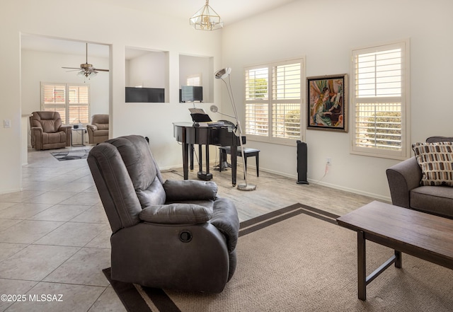 tiled living room with ceiling fan with notable chandelier