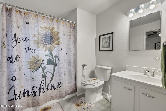 bathroom featuring ceiling fan, vanity, a shower with shower curtain, and toilet