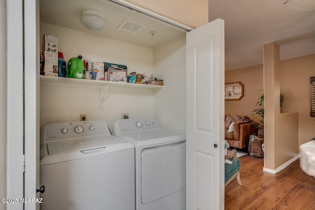 laundry area featuring washing machine and dryer and light hardwood / wood-style flooring