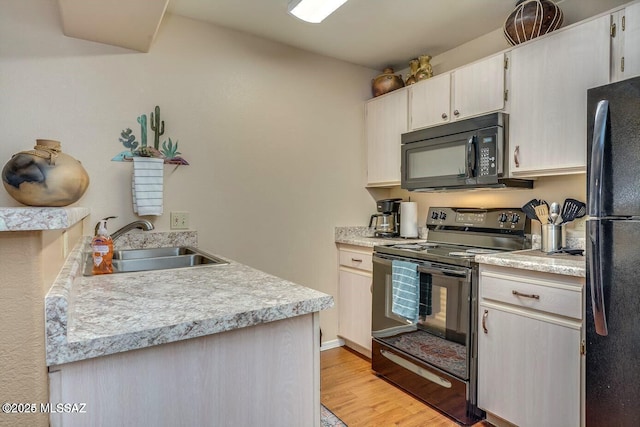 kitchen featuring sink, black appliances, and light hardwood / wood-style flooring