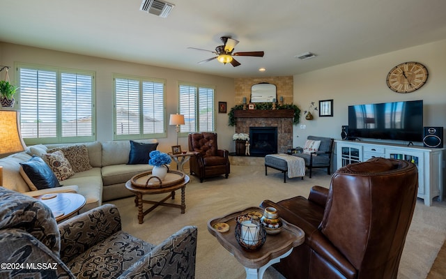 living room with a stone fireplace, ceiling fan, light carpet, and a wealth of natural light