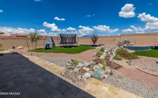 view of yard with a trampoline and a patio