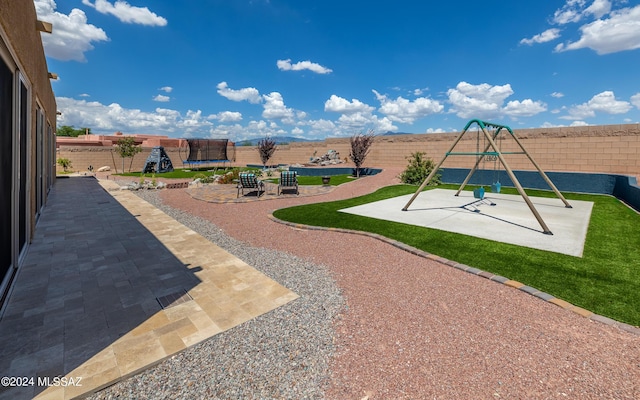 view of jungle gym featuring a trampoline and a patio area