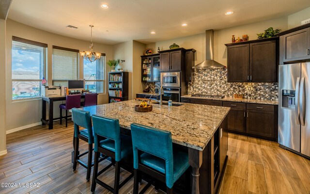 kitchen featuring decorative backsplash, appliances with stainless steel finishes, wall chimney exhaust hood, sink, and wine cooler