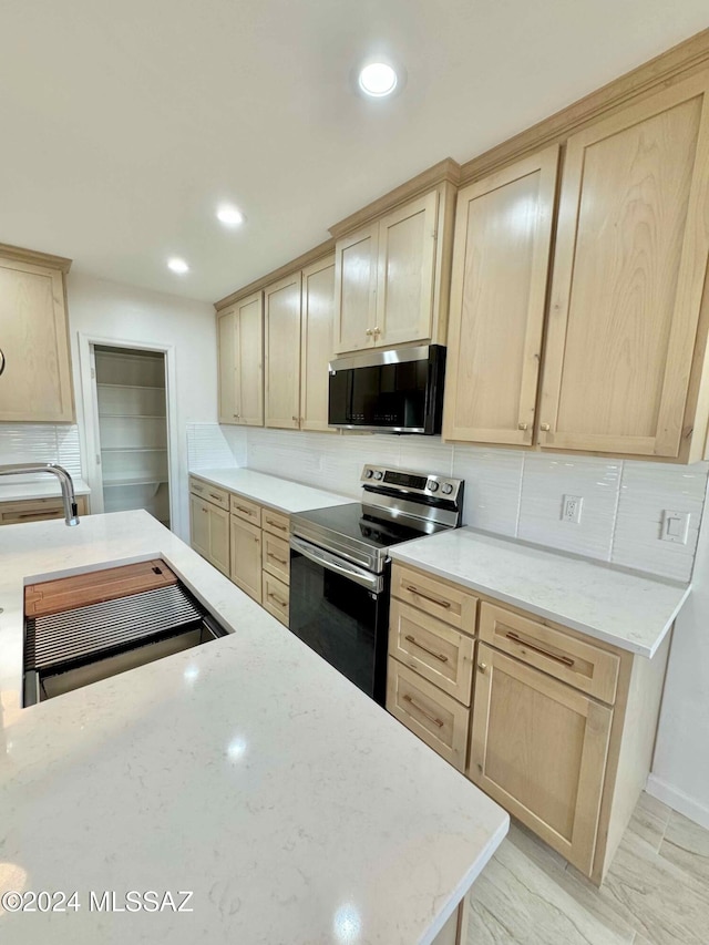 kitchen with decorative backsplash, light brown cabinetry, and appliances with stainless steel finishes