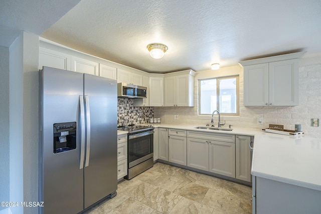 kitchen featuring backsplash, sink, a textured ceiling, white cabinetry, and stainless steel appliances