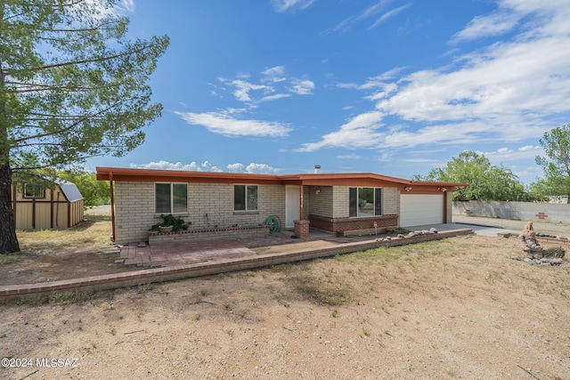 ranch-style house featuring a garage and a storage unit