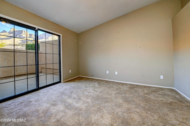 unfurnished room with a mountain view, carpet floors, and vaulted ceiling