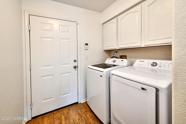 washroom featuring dark hardwood / wood-style flooring, cabinets, and washing machine and clothes dryer