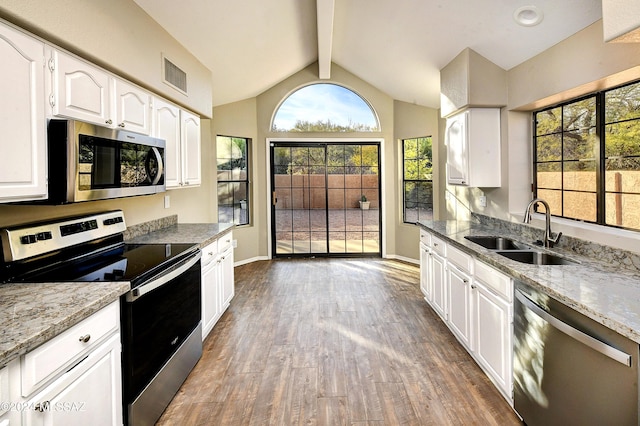 kitchen with white cabinets, stainless steel appliances, light stone counters, and sink