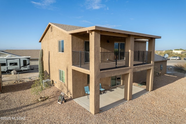 rear view of house with stucco siding and a patio